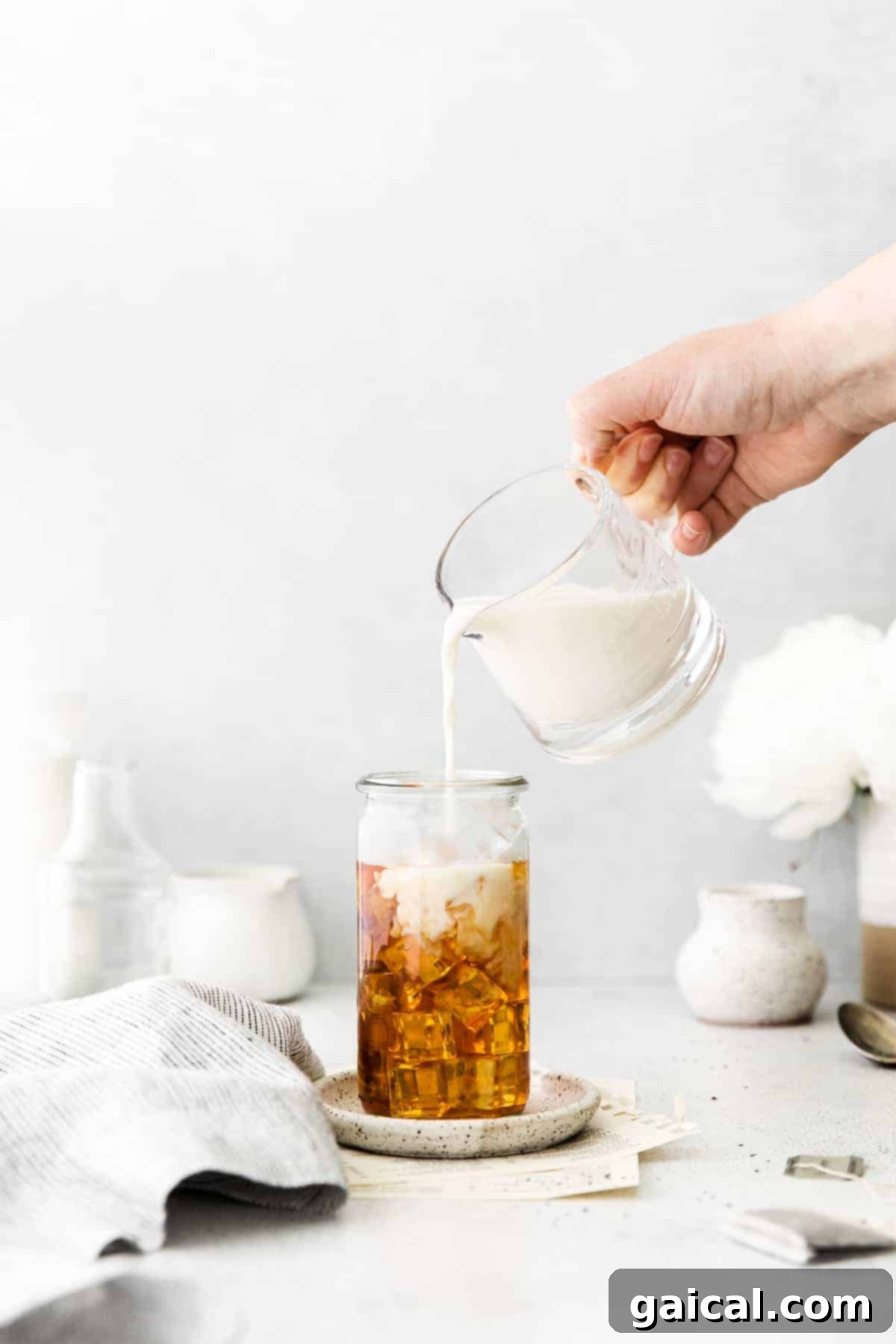 Adding Milk to Complete Your Iced London Fog Latte Pouring milk over iced Earl Grey tea, creating a beautiful layered effect.