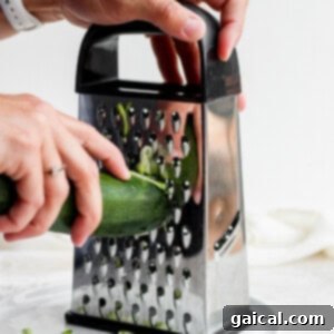 Hands shredding zucchini.