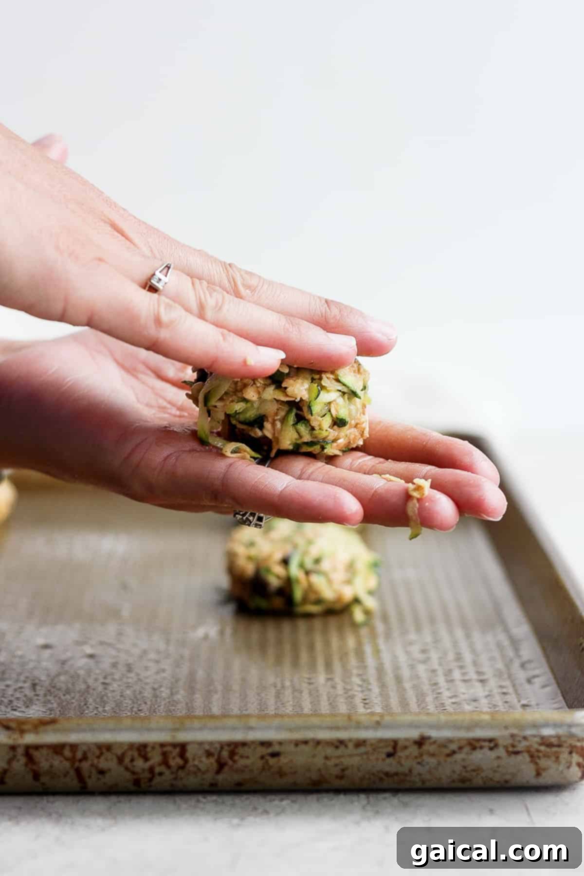 Shaping cookie dough by hand. Hands gently pressing down a ball of cookie dough to flatten it before baking.