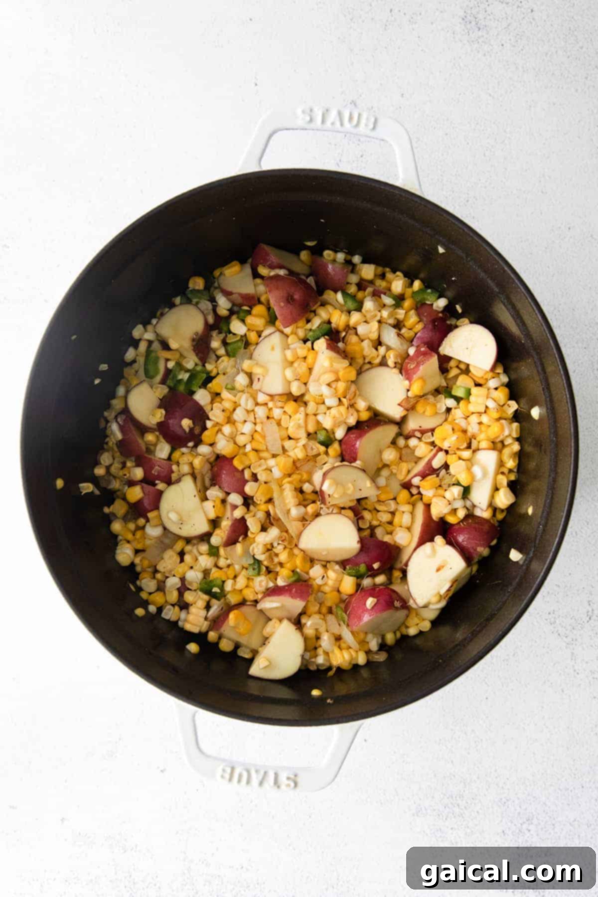 Sautéing Aromatics for Corn Chowder Minced onions and garlic sautéing in a Dutch oven, creating an aromatic base for the corn chowder.