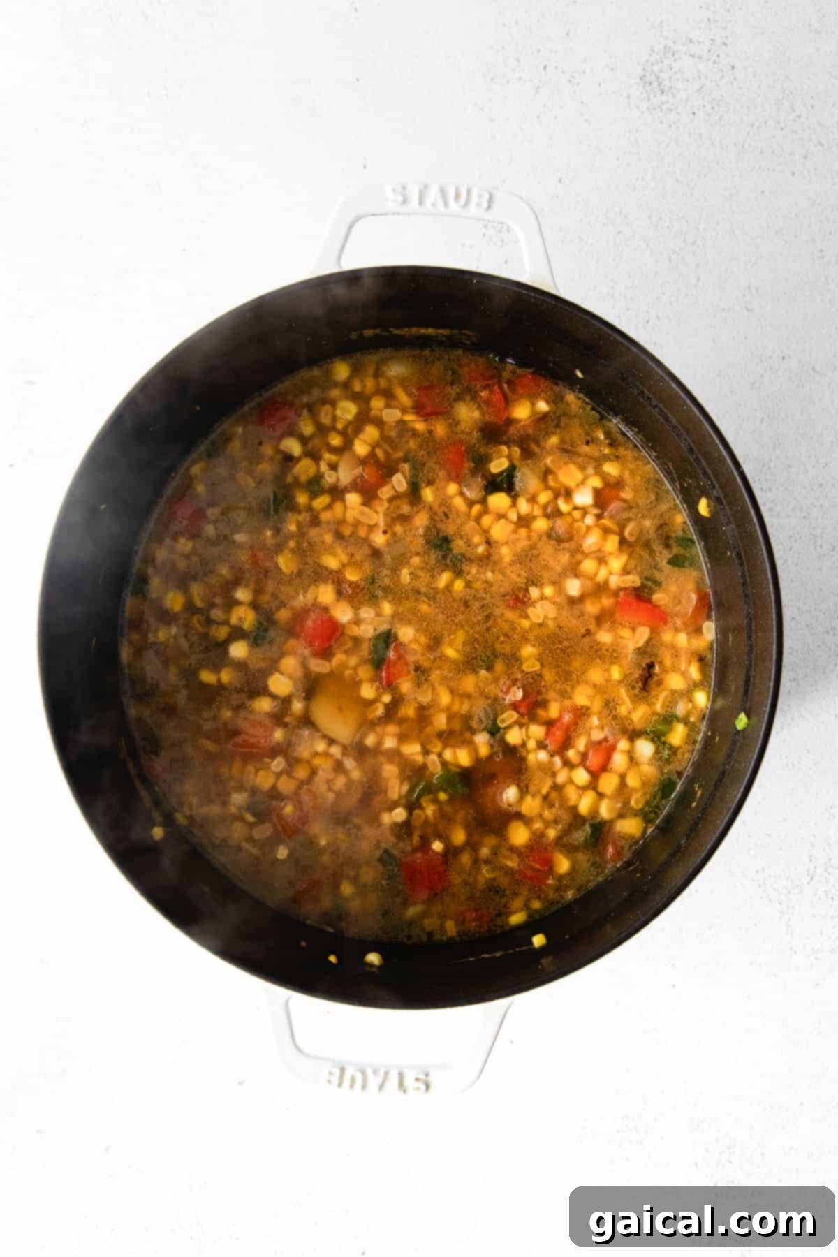 Simmering Corn Chowder in a Dutch Oven A large Dutch oven filled with simmering corn chowder, rich and creamy, with visible kernels of corn and potato chunks.