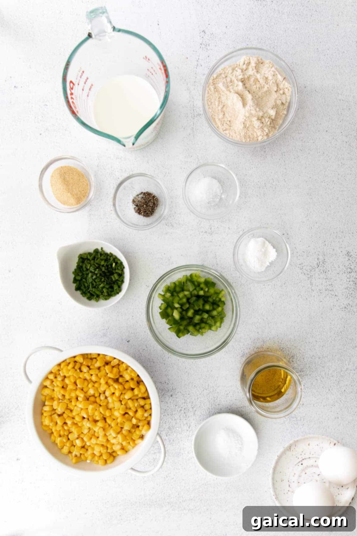 A vibrant selection of corn, fresh chives, pickled jalapeños, olive oil, and various spices, all ready to be combined for the delicious corn fritters recipe.