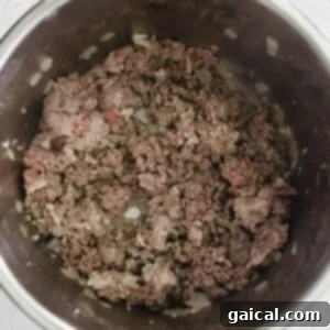 Bowl of instant pot chili with ground beef on a white surface.