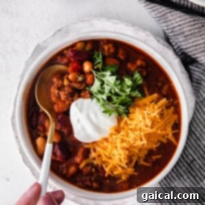 a person holding a bowl of instant pot chili with sour cream.
