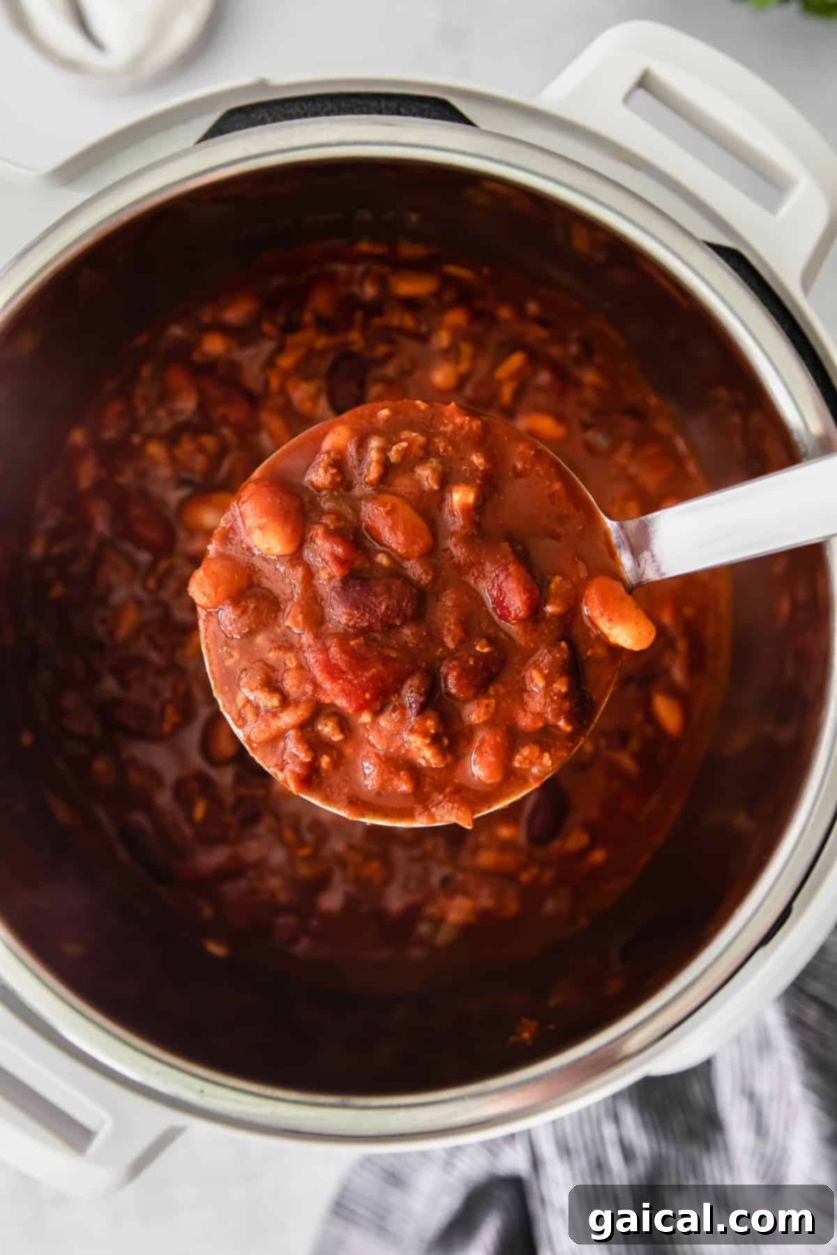 A ladle scooping rich, thick Instant Pot chili from the pot, showcasing its texture.
