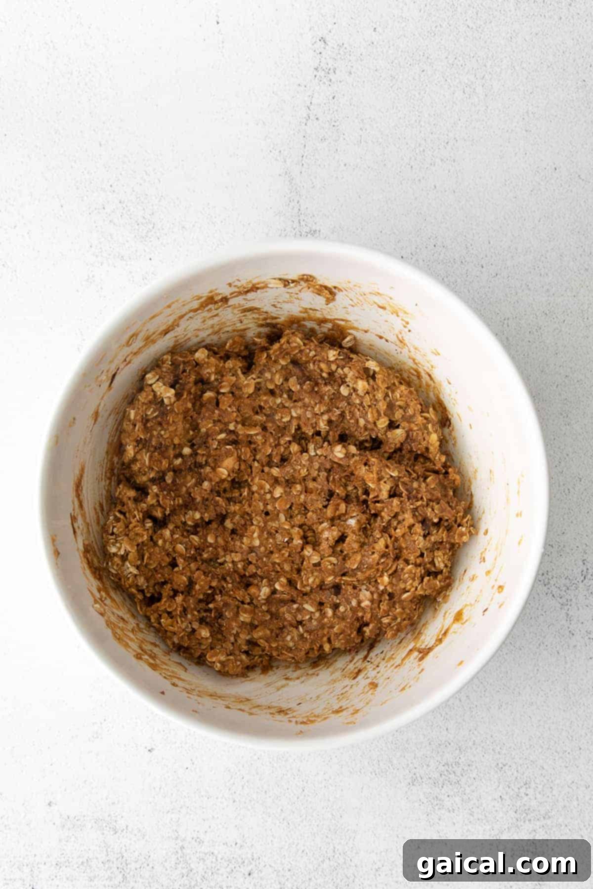 Preparing the Granola Bar Mixture in a Bowl Granola bar mixture with oats, peanut butter, honey, and chocolate chips being stirred in a large mixing bowl.