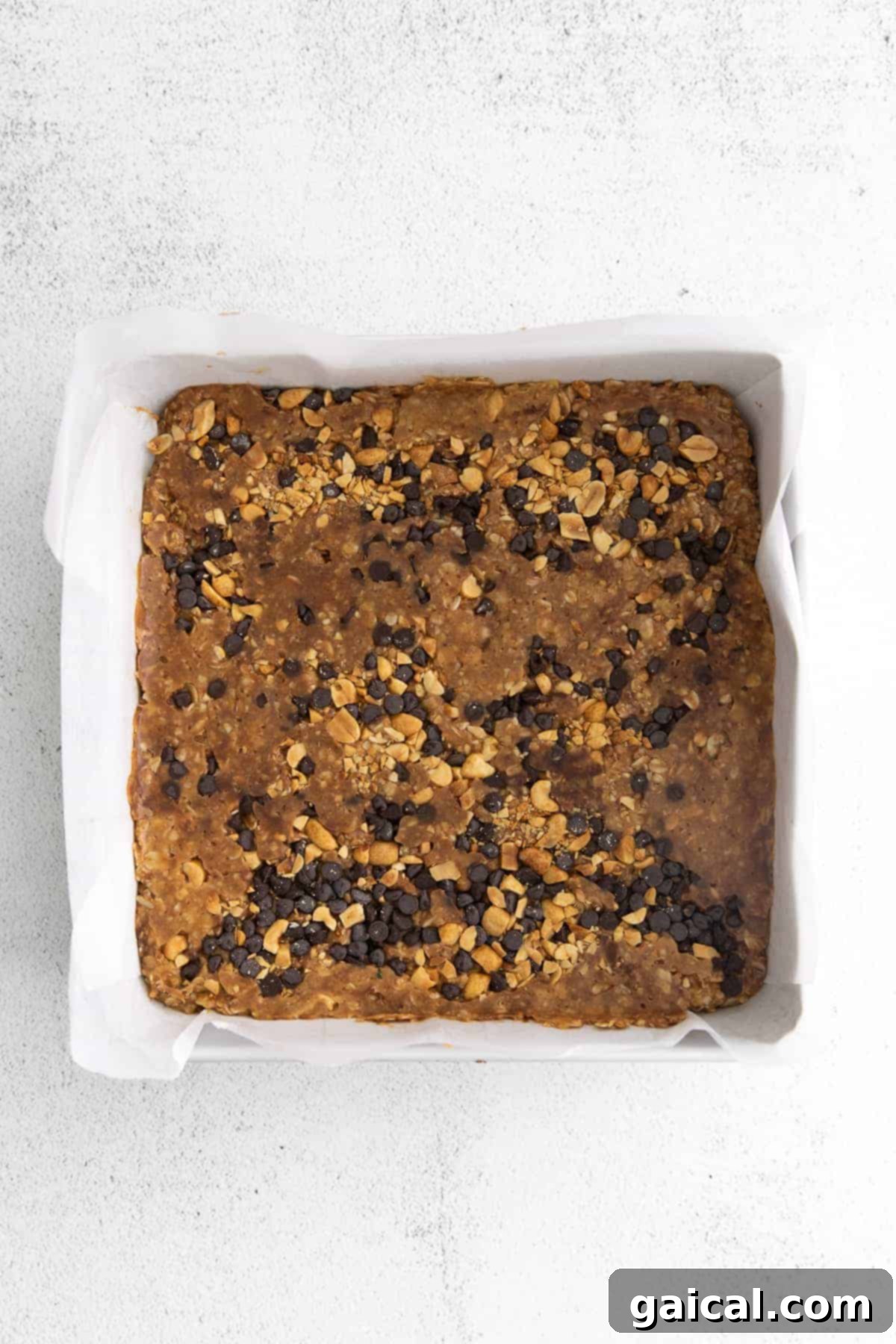 Set Peanut Butter Granola Bars in Pan Freshly made no-bake granola bars, sweetened with honey and featuring peanut butter, rolled oats, and chocolate chips, arranged in a baking dish.