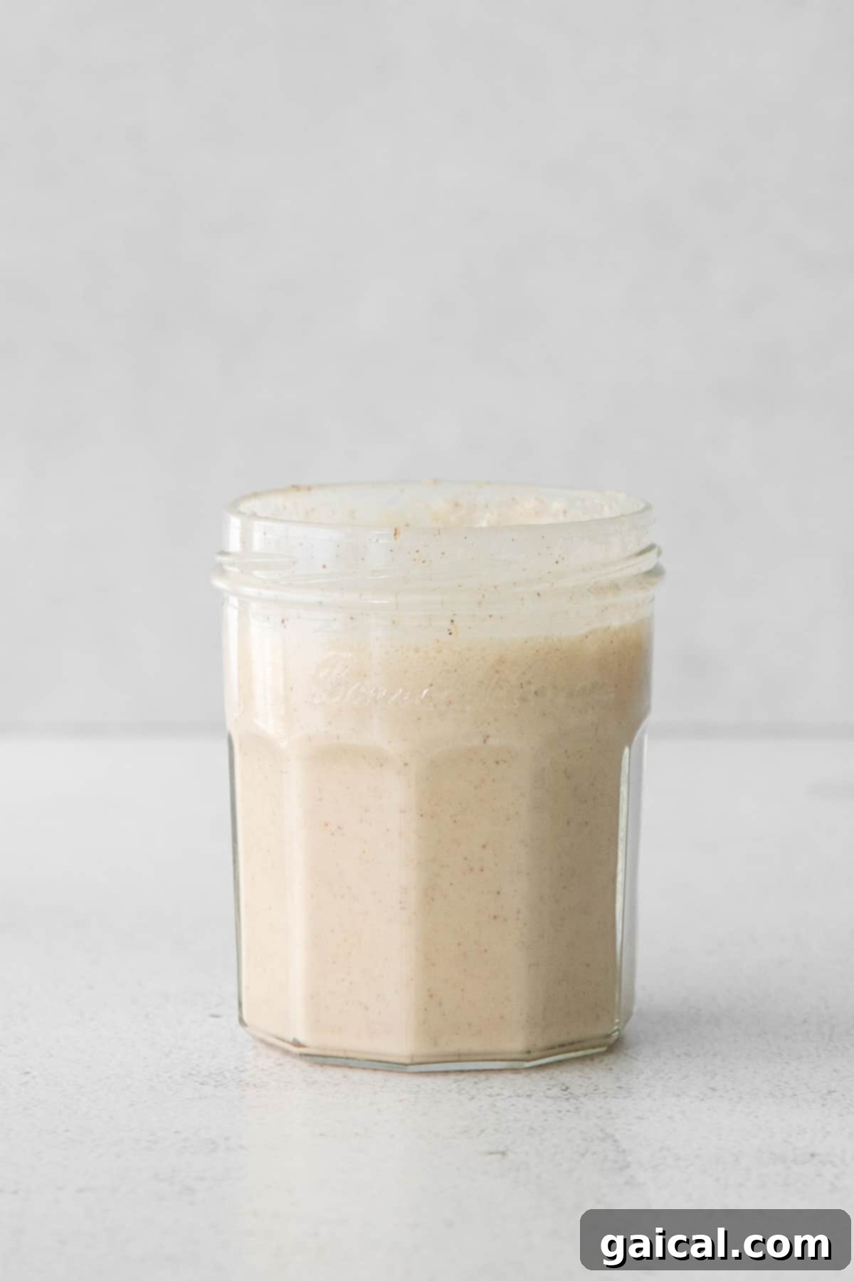 Rich pumpkin cream mixture in a clear glass jar.