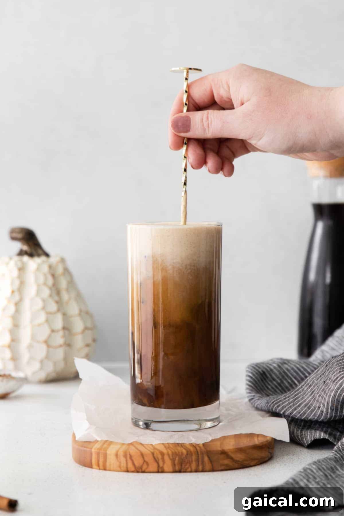 Stirring a glass of Pumpkin Cream Cold Brew with a tall straw.