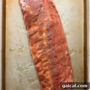 Ribs on a baking sheet, drizzled with oil and covered with foil for baking.