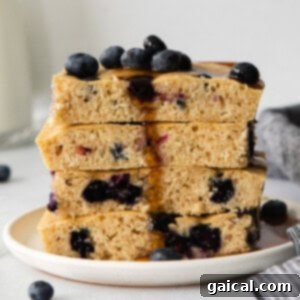 A stack of blueberry pancakes on a plate, ready to be served.