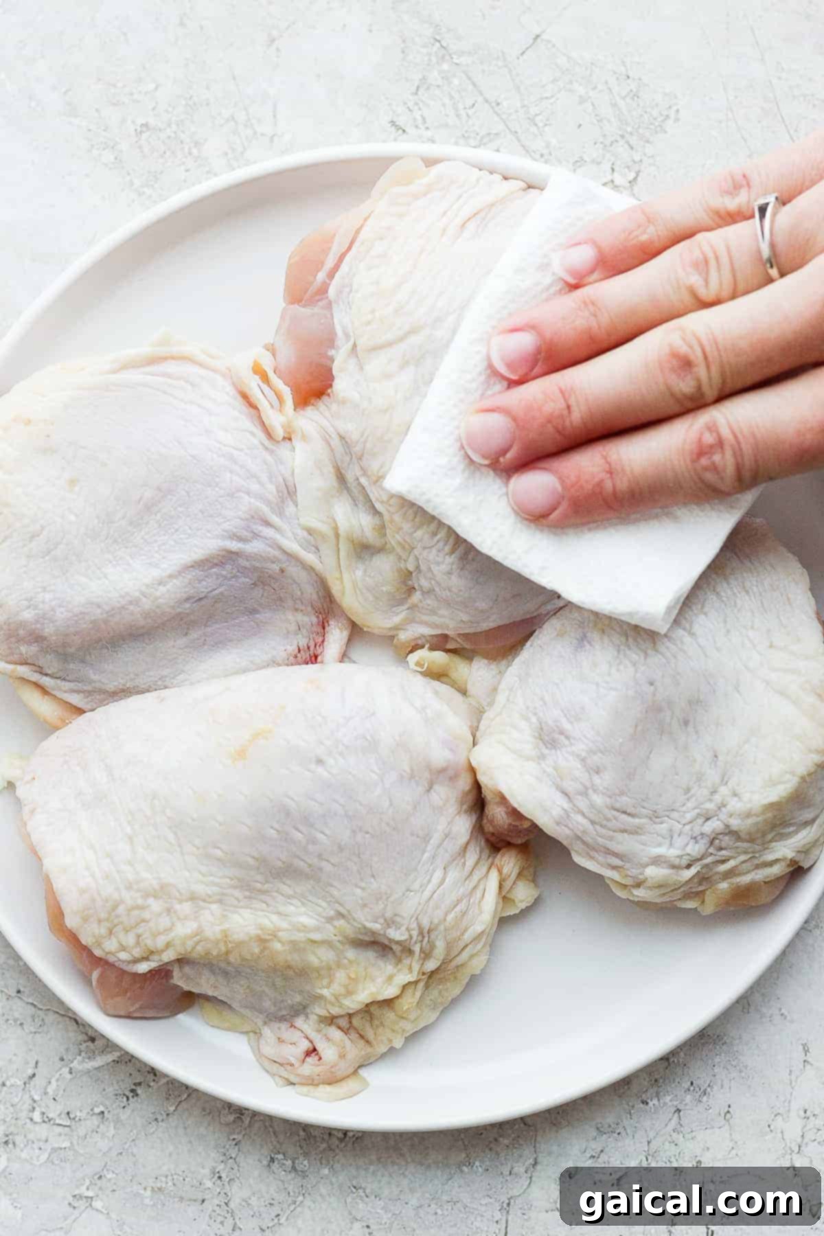 Patting chicken thighs dry with a paper towel before seasoning