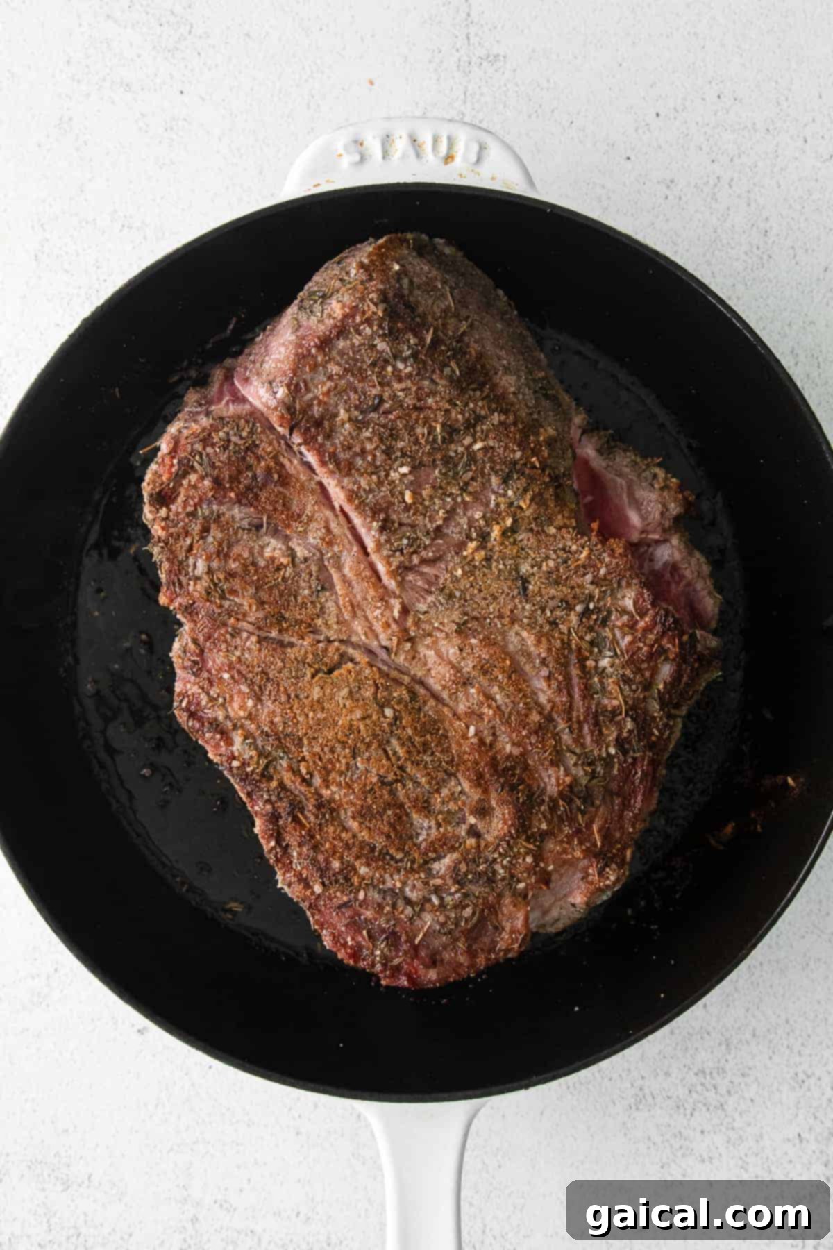 A thick cut of chuck roast being expertly seared in a hot cast iron skillet, developing a rich, brown crust.