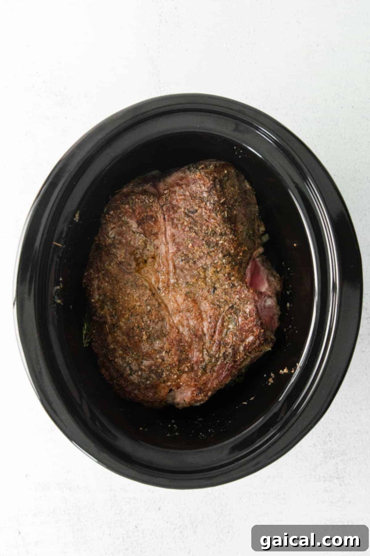 A perfectly cooked chuck roast nestled in a slow cooker, surrounded by savory broth and mushrooms, ready for shredding.