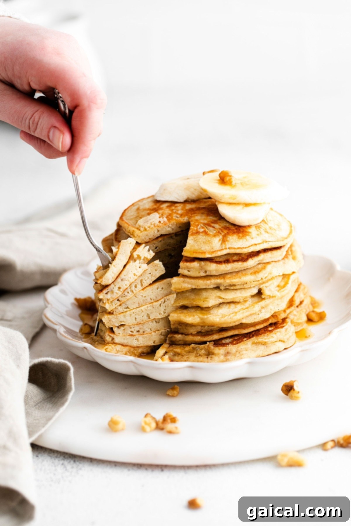 Nourishing Banana Pancakes 9 A fork piercing into a stack of banana pancakes, showing their fluffy texture and deliciousness.