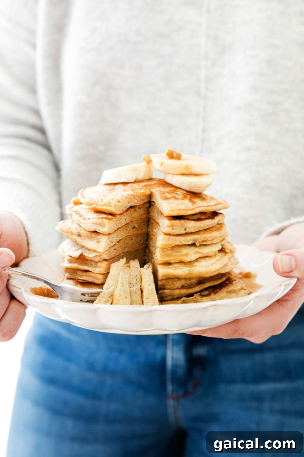 Nourishing Banana Pancakes 11 A hand holding a plate of easy and fluffy banana pancakes, ready to be enjoyed.