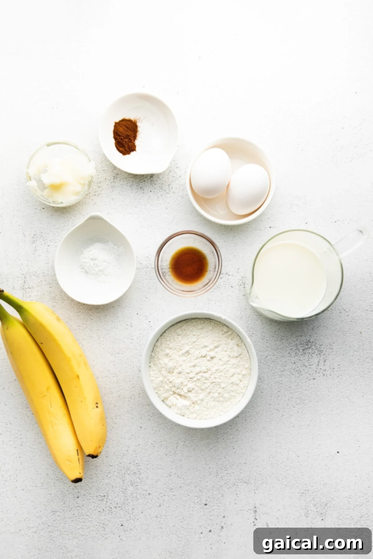 Nourishing Banana Pancakes 3 Various healthy ingredients for banana pancakes laid out on a kitchen counter, including whole wheat flour, ripe bananas, eggs, and almond milk.