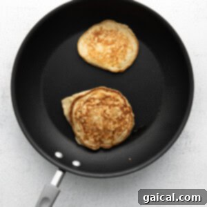 Pancakes cooking on a stove top griddle.