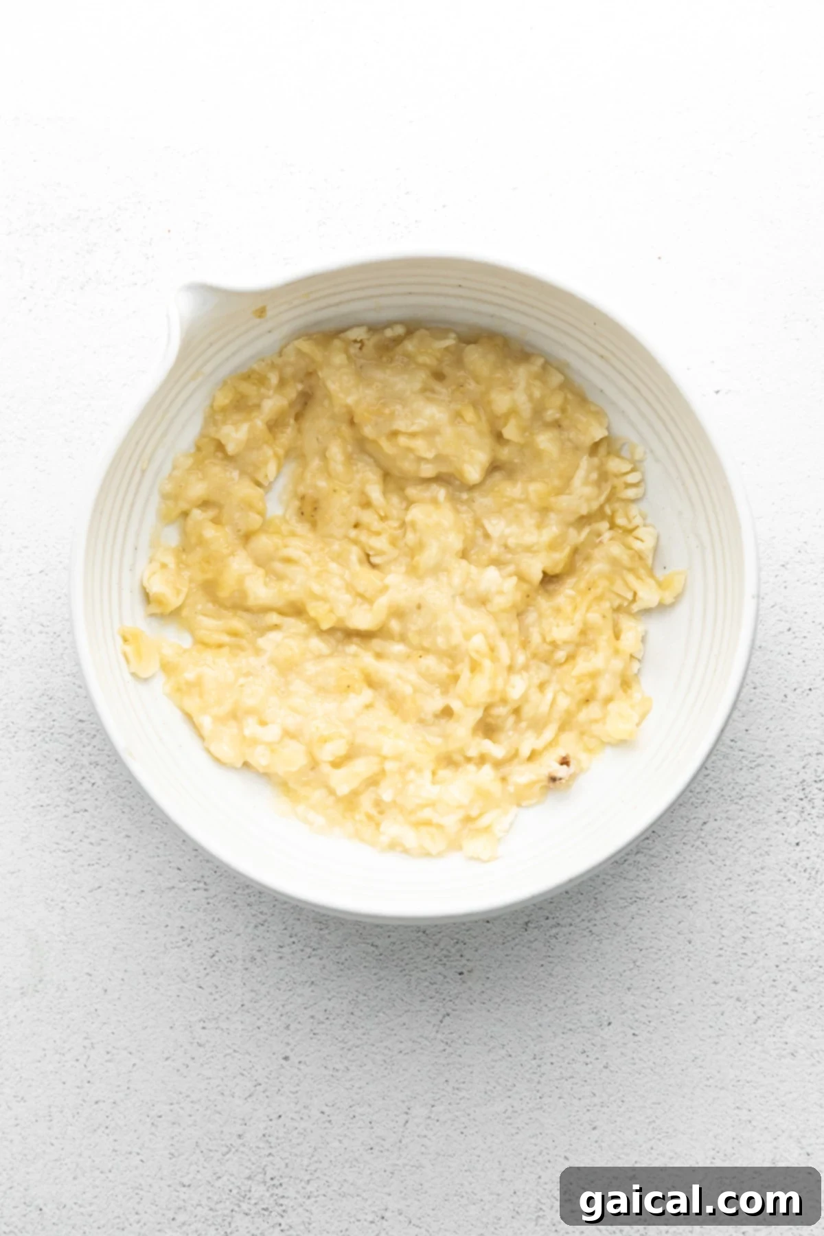 Nourishing Banana Pancakes 4 Perfectly mashed ripe bananas in a bowl, ready for mixing into pancake batter.