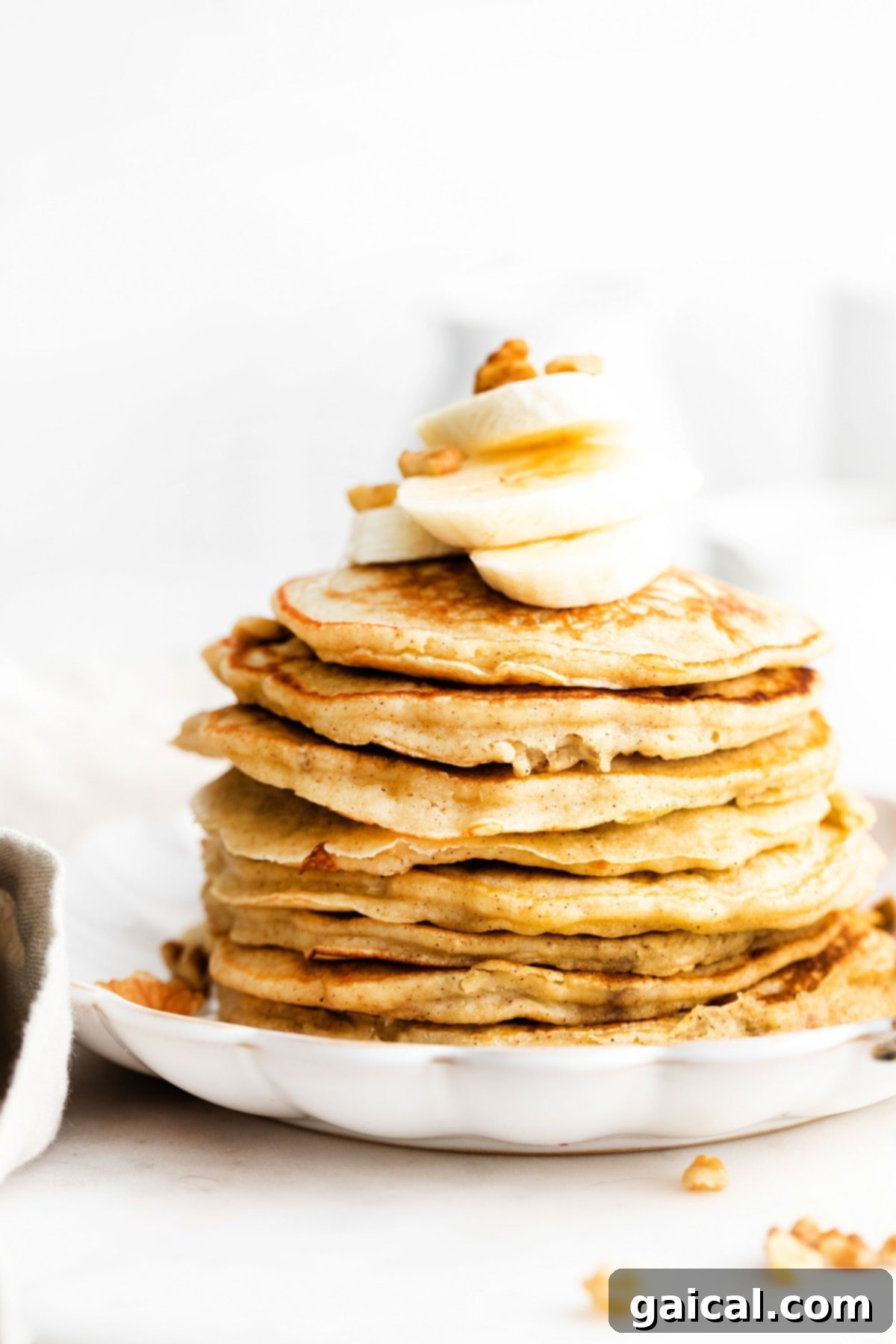 Nourishing Banana Pancakes 8 A stack of perfectly cooked banana pancakes, topped with fresh banana slices and a generous drizzle of syrup.