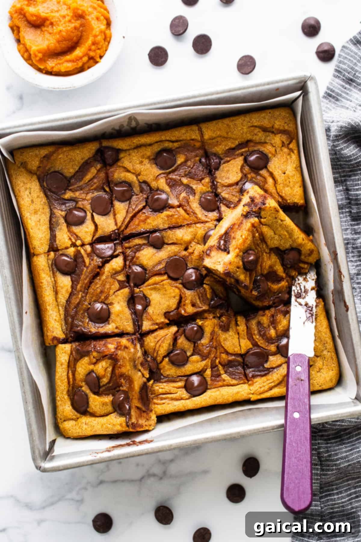 Marbled Brown Sugar Pumpkin Breakfast Cake 2 Pumpkin chocolate chip bars in a baking pan with a knife.