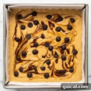 Marbled Brown Sugar Pumpkin Breakfast Cake 10 A brownie with chocolate chips and caramel sauce in a baking pan.