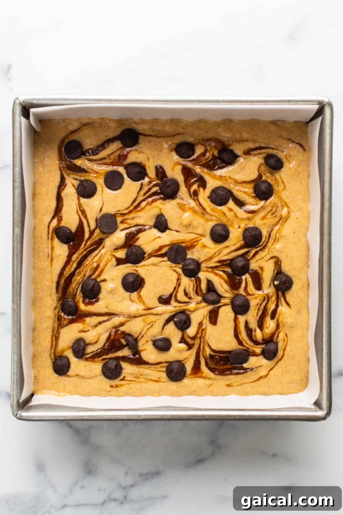 Marbled Brown Sugar Pumpkin Breakfast Cake 4 A brownie with chocolate chips and caramel sauce in a baking pan.