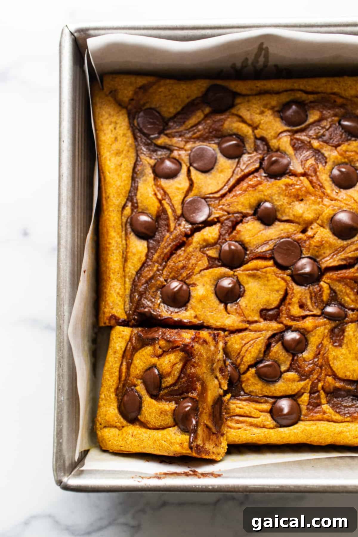 Marbled Brown Sugar Pumpkin Breakfast Cake 5 Pumpkin cheesecake bars in a baking pan with chocolate chips.