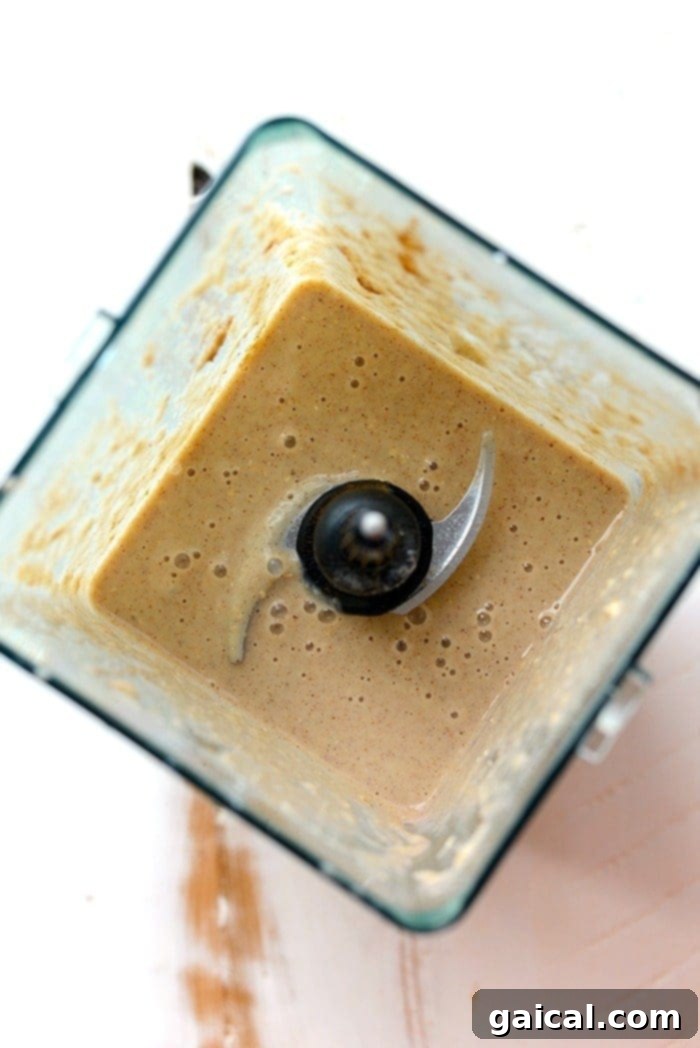 All the ingredients for an apple pie smoothie bowl being blended together in a high-speed blender, creating a smooth mixture.