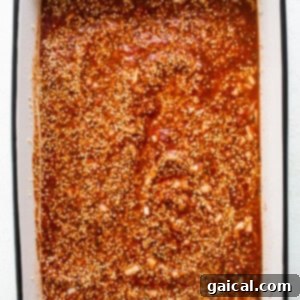 A baking dish filled with sauce and spices, showing the initial mixture before baking.