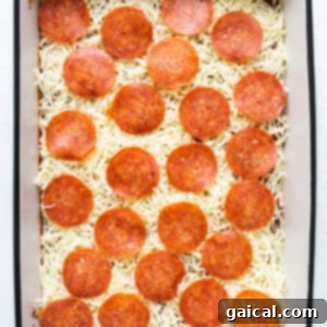 Pepperoni pizza in a baking dish with cheese on top, ready for final baking.