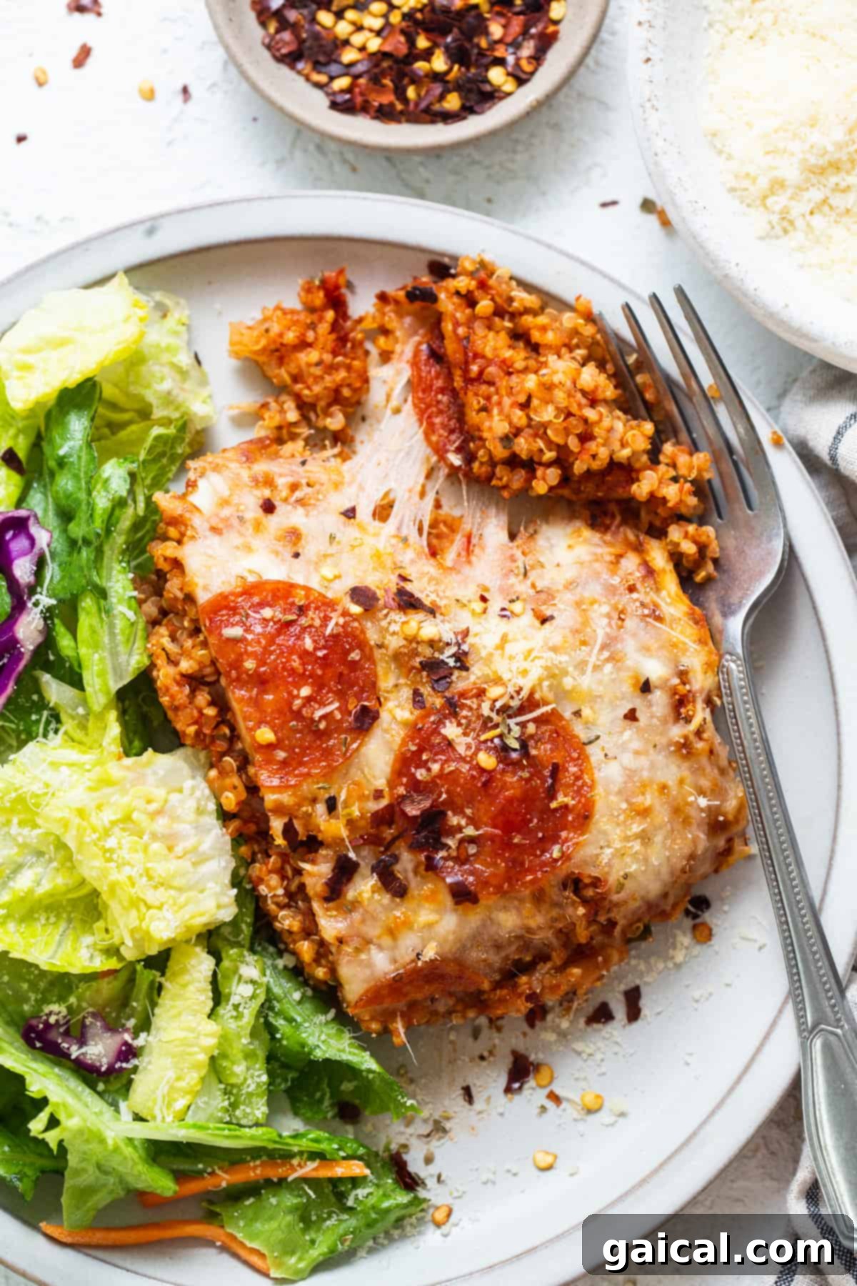 Wholesome Quinoa Pizza Bake 6 A serving of pepperoni pizza quinoa casserole alongside a fresh green salad, making a complete healthy meal.