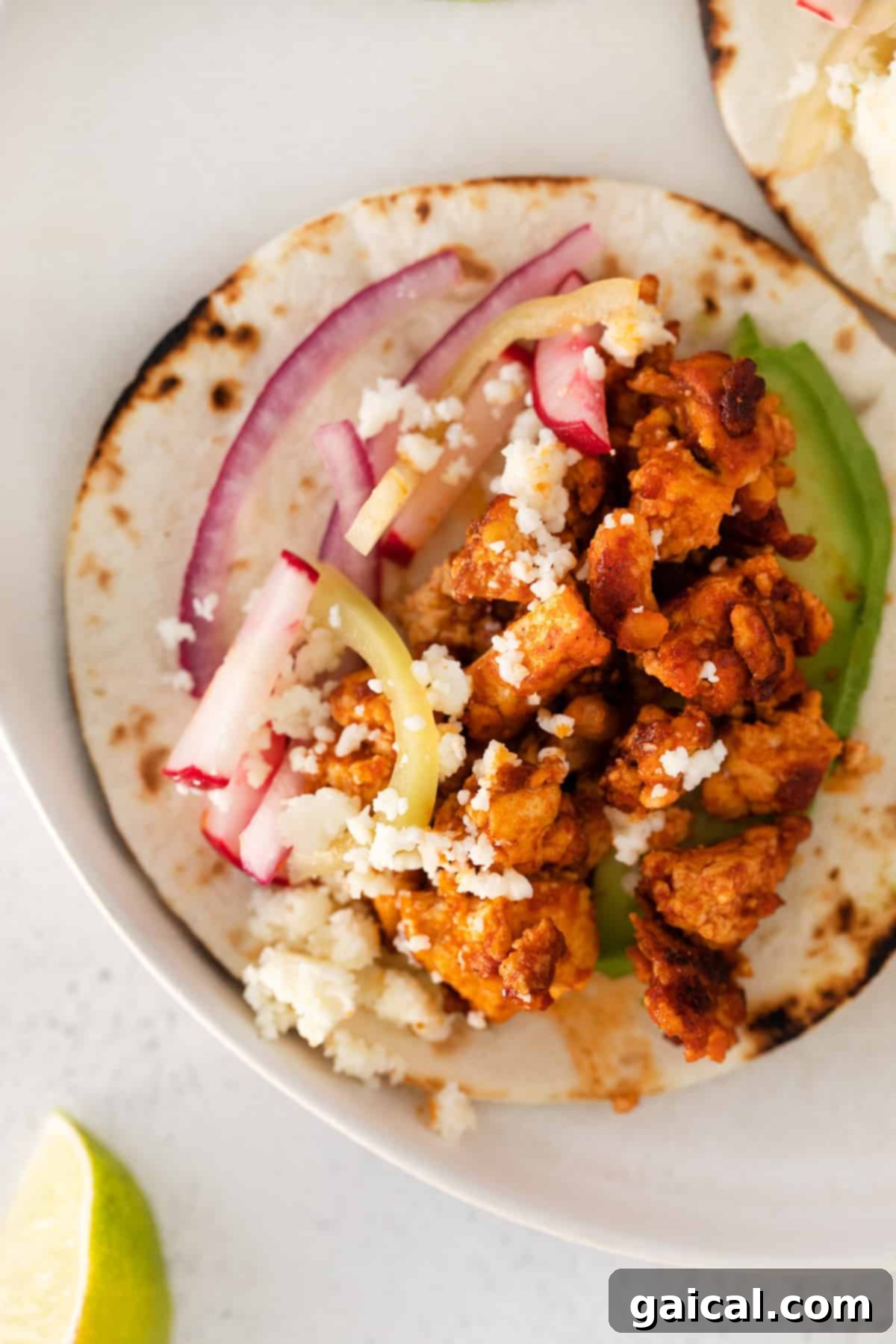 Close-up of a tofu taco nestled in a soft flour tortilla, showcasing the filling.