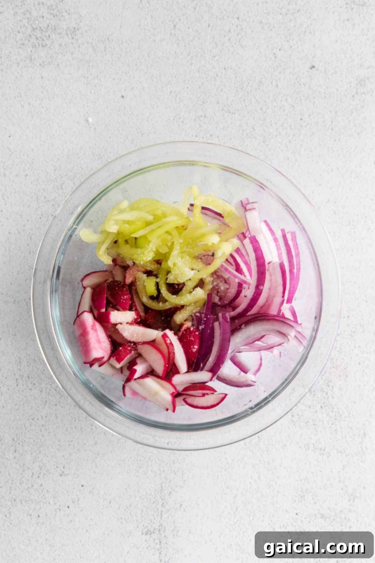 A vibrant radish slaw featuring crisp radishes, sliced banana peppers, and thinly cut red onion.
