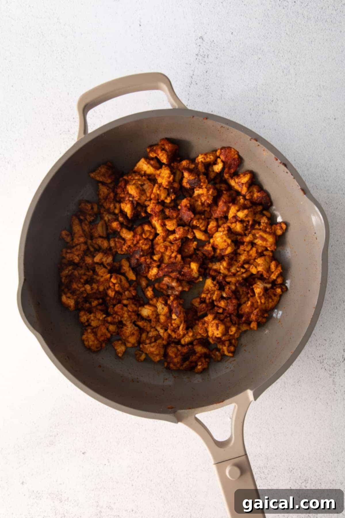 Seasoned tofu crumble, rich in color, sizzling in a pan with walnuts.