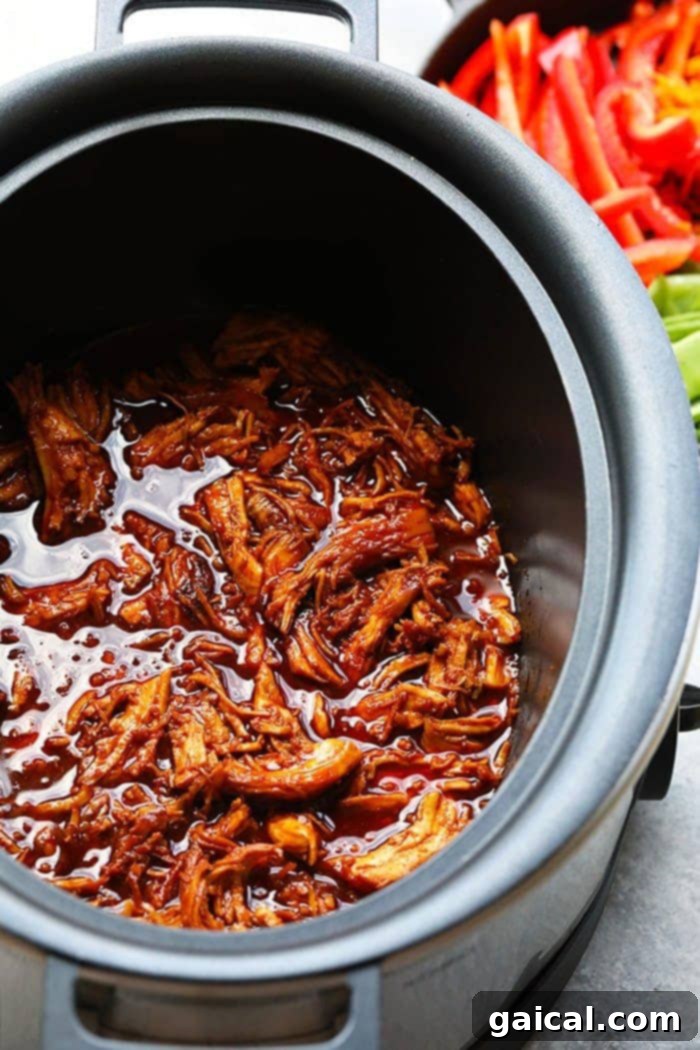 Sticky Honey Sriracha Chicken 2 Honey Sriracha Chicken simmering in a slow cooker, showcasing its rich, sticky sauce and tender chicken pieces, ready to be shredded.
