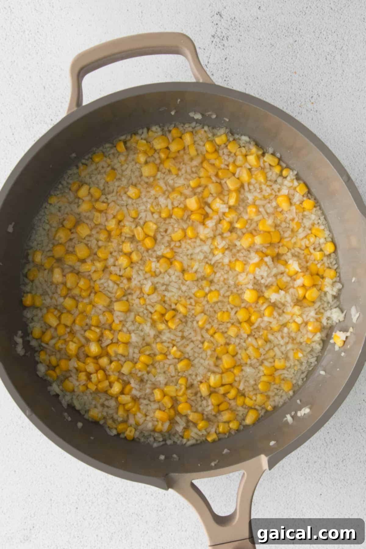 Close-up of frozen riced cauliflower and corn in a skillet, steaming.