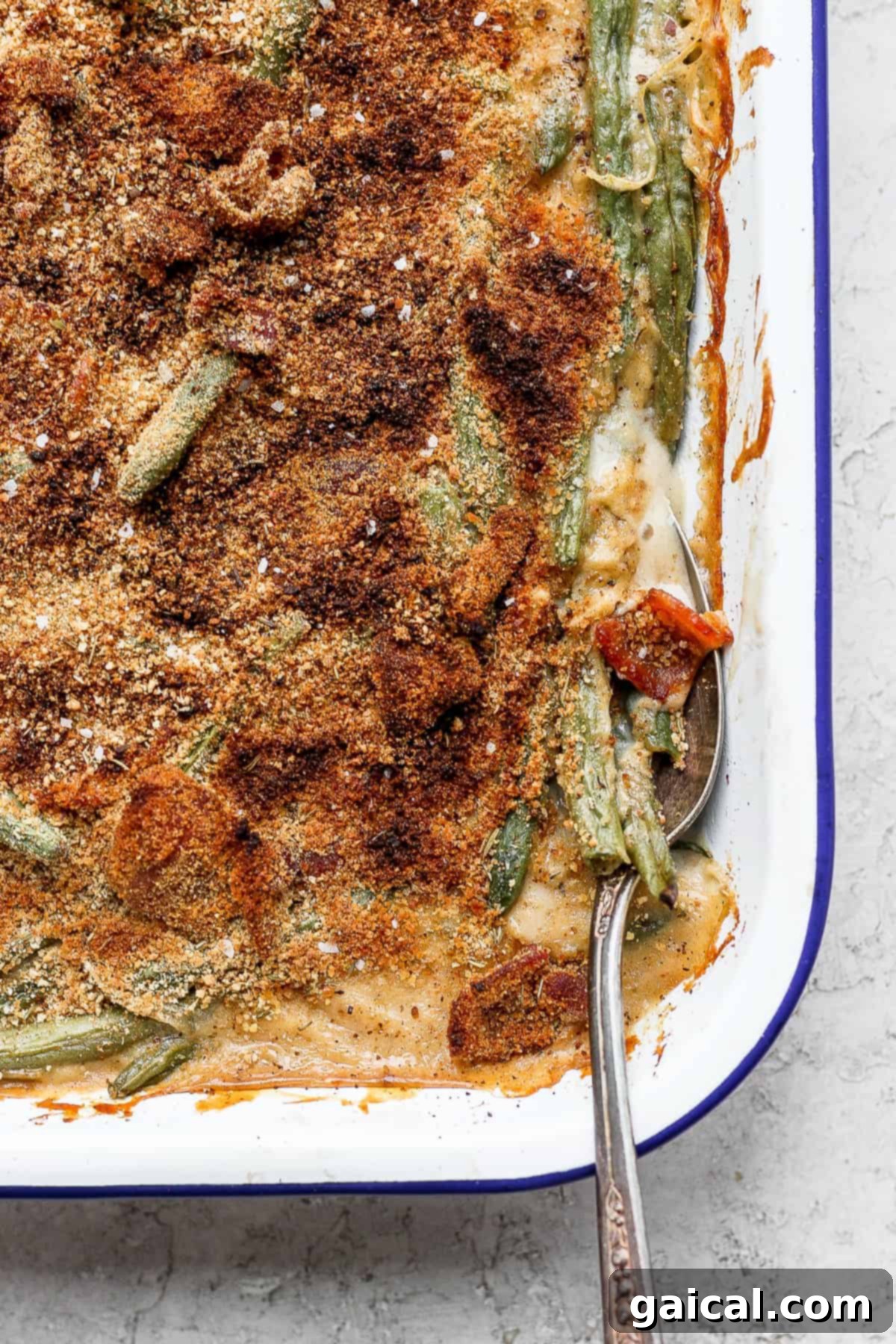 This green bean casserole with bacon is a homemade version of a classic recipe, but instead of using a cream of mushroom soup it features an amazing bacon roux. green bean casserole with bacon on a spoon