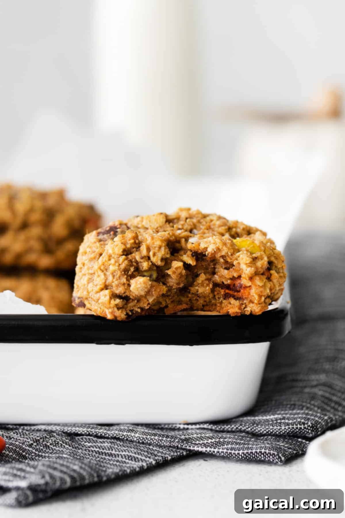 A batch of fall cookies doesn't get much better than Pumpkin Monster Cookies! A Pumpkin Monster Cookie with a bite taken out, showing its chewy interior