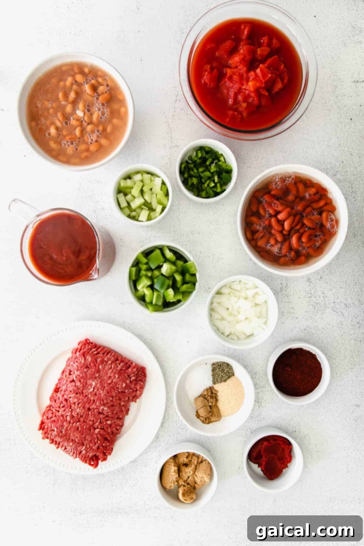 A vibrant array of fresh ingredients for Wendy's copycat chili, including ground beef, diced vegetables, and various spices, laid out on a kitchen counter.