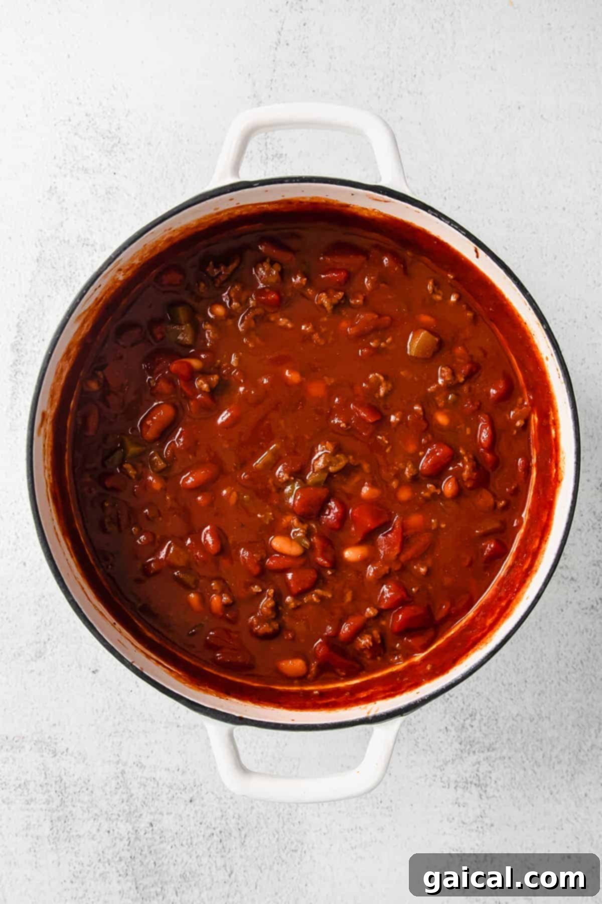 A large stockpot brimming with rich, bubbling chili on the stovetop.