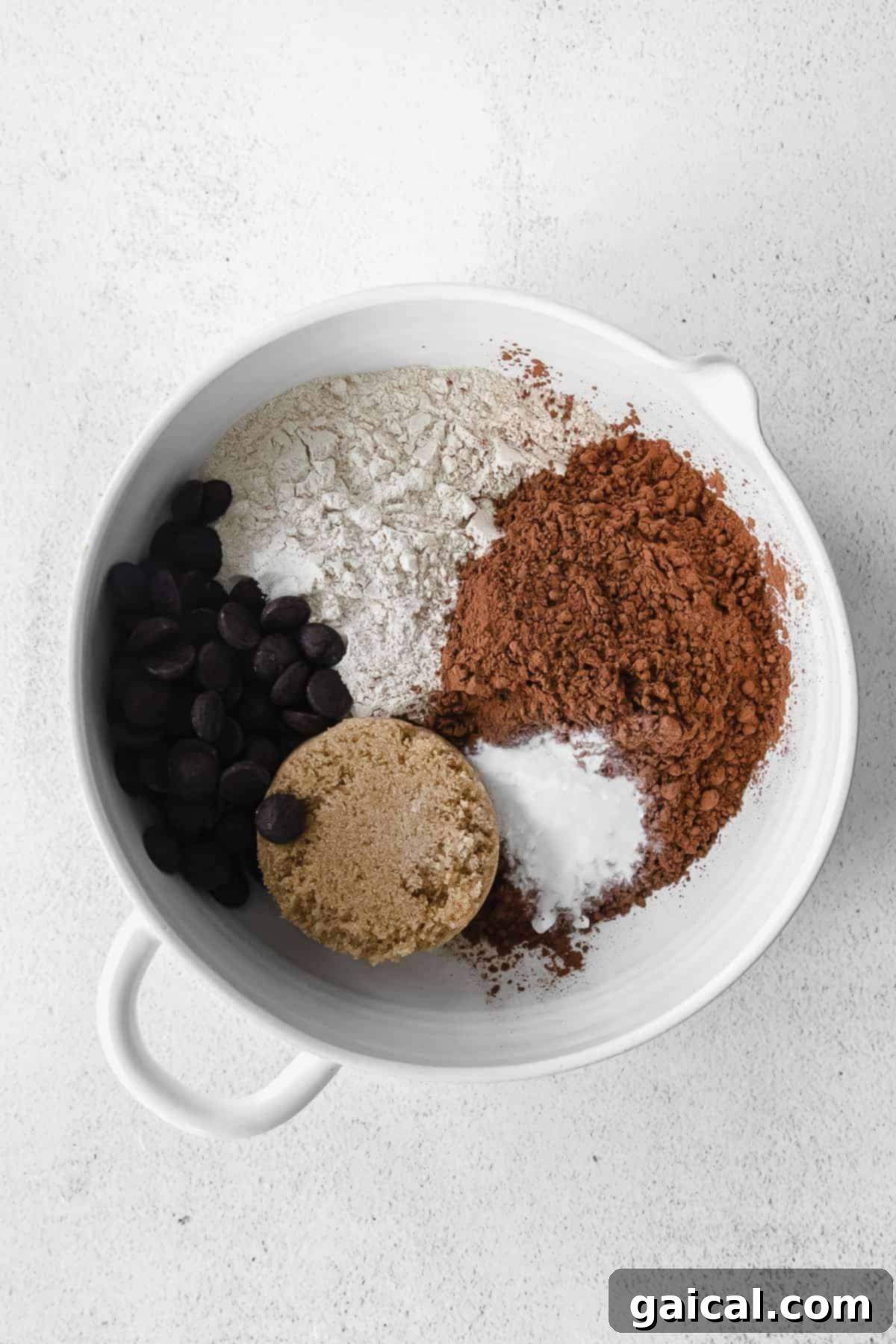 Dry ingredients for chocolate pumpkin bread, including flour, cocoa powder, and brown sugar, mixed in a large bowl.