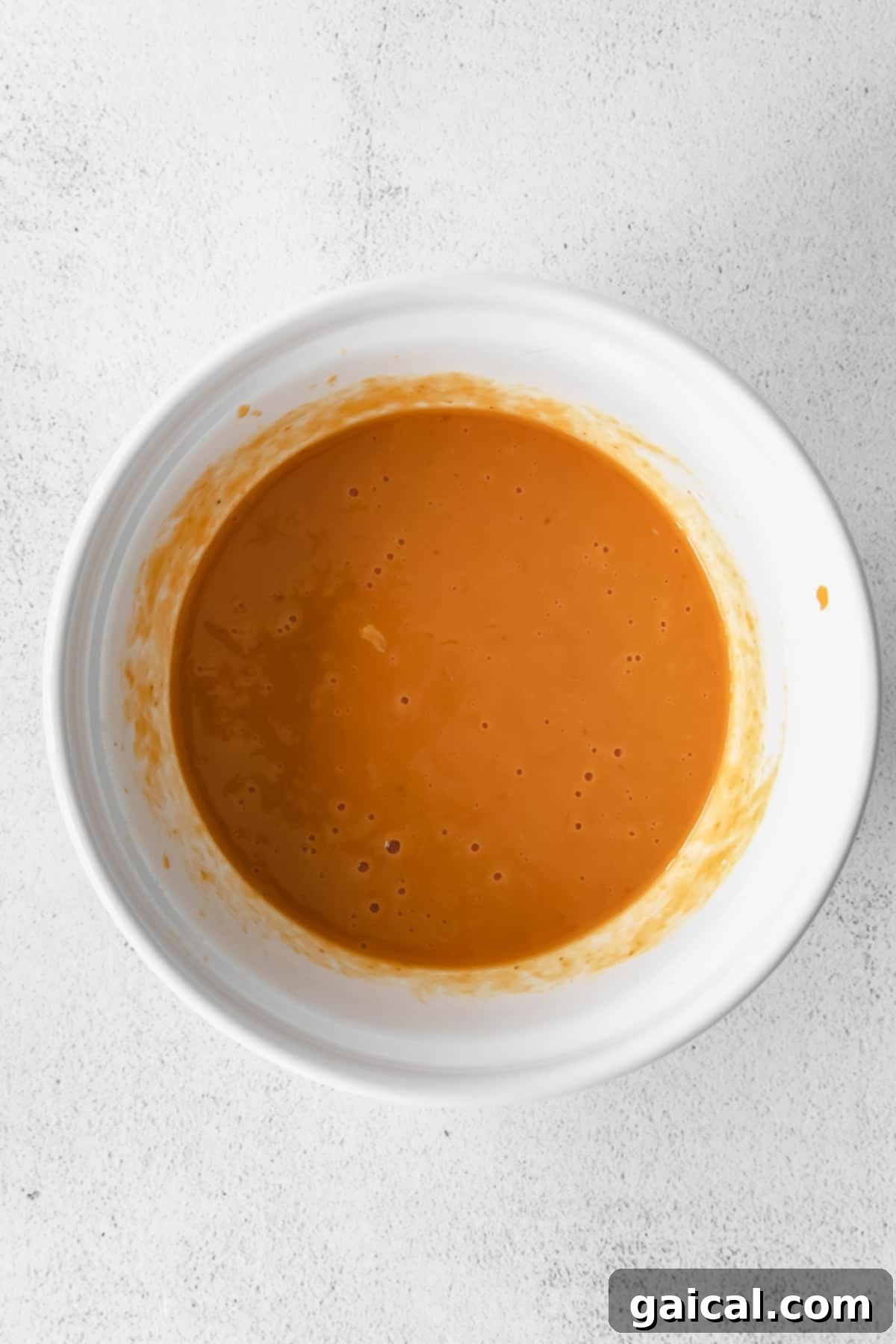 Wet ingredients for chocolate pumpkin bread, including pumpkin puree and almond milk, mixed in a bowl.
