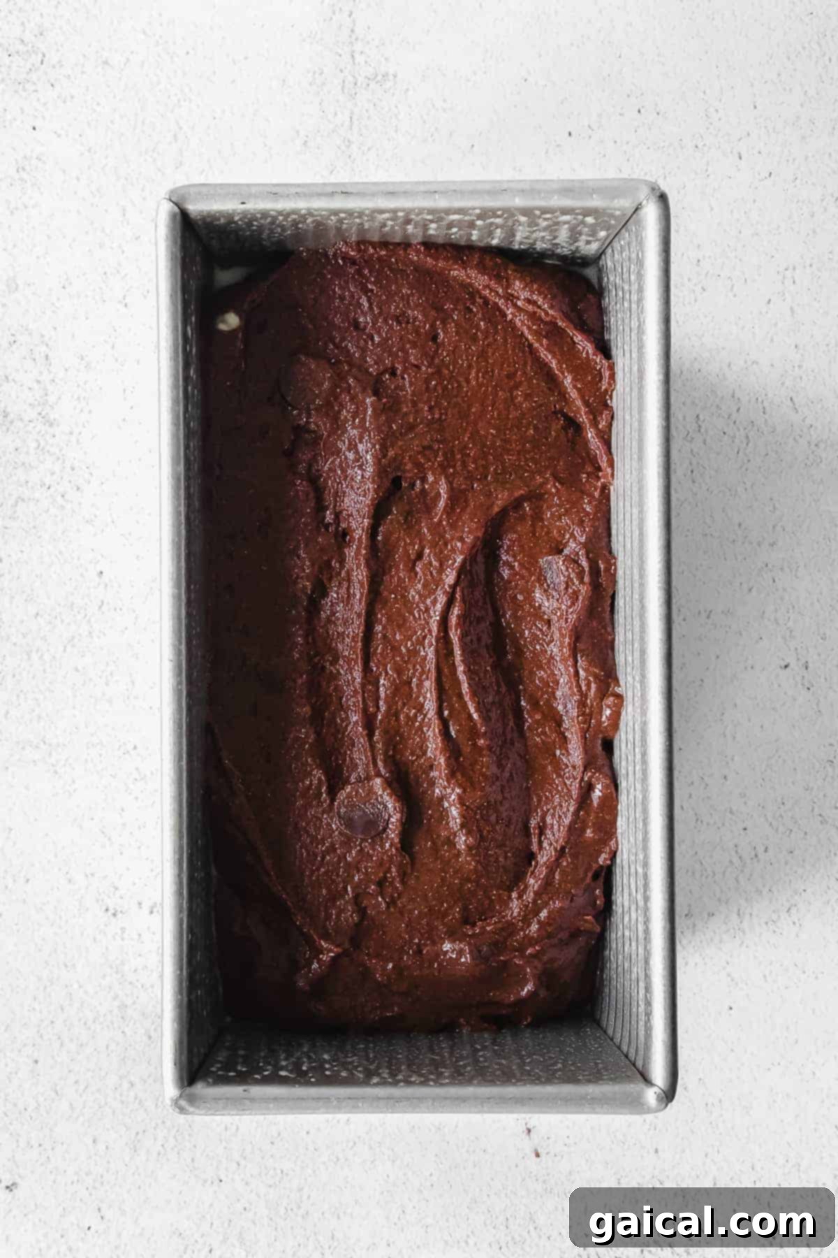 A thick, rich chocolate pumpkin bread batter ready to be poured into a loaf pan.