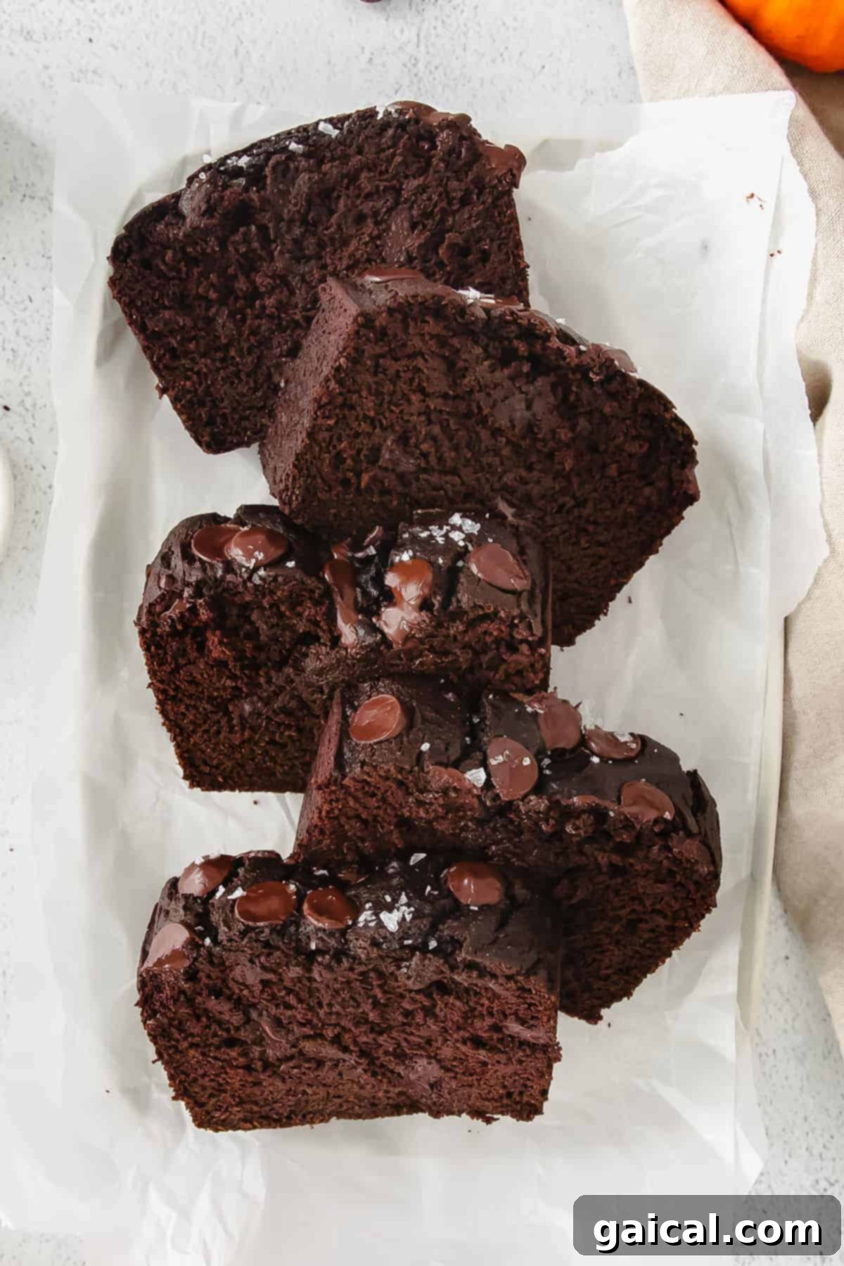 Individual slices of chocolate pumpkin bread neatly arranged on parchment paper, ready to be enjoyed or stored.