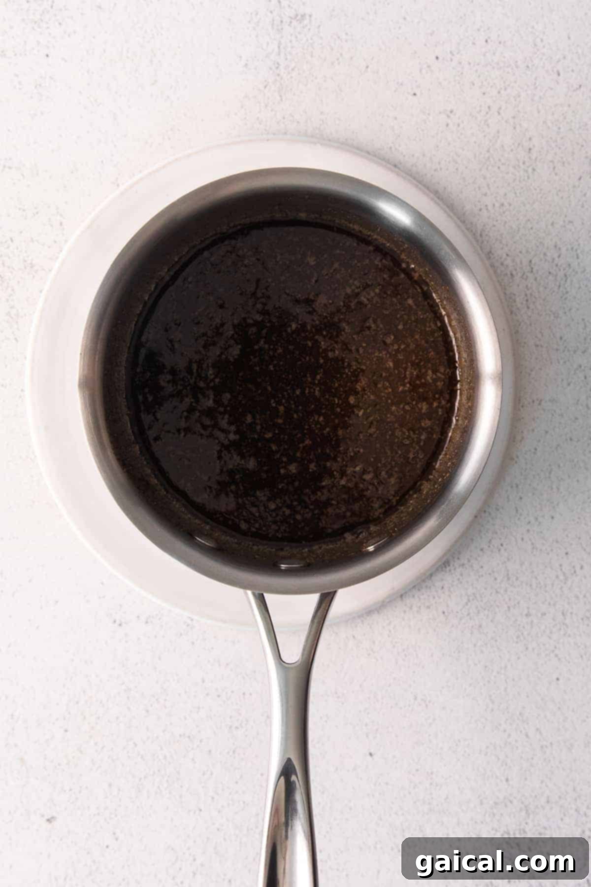 Maple Chai Chex Crunch 5 A small saucepan on the stove, containing the simmering chai-spiced butter and maple syrup mixture, ready to be poured over the dry ingredients.