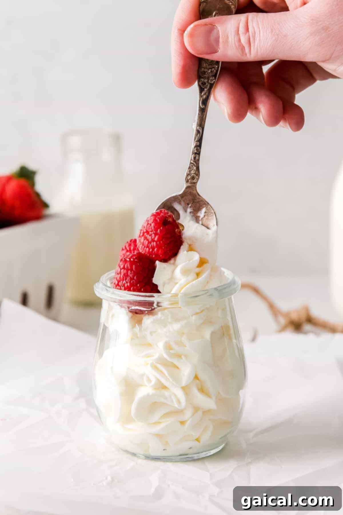 Mastering Whipped Cream from Scratch 6 A spoon full of whipped cream and fresh raspberries.