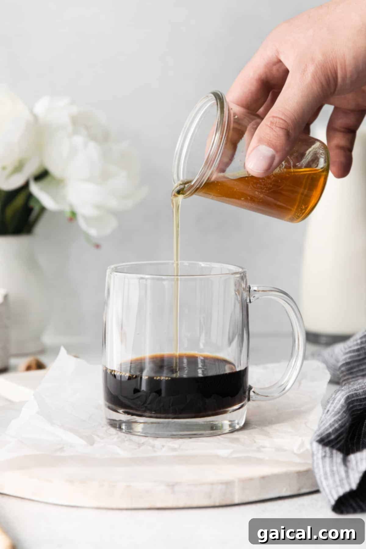 Mixing espresso and honey simple syrup for your miel. Espresso being poured into a mug, followed by a stream of golden honey simple syrup, essential steps for a delicious miel.