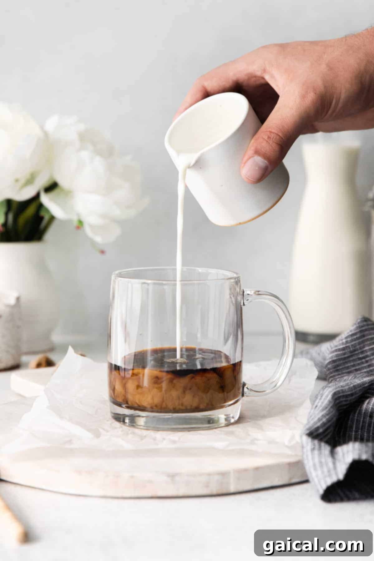 The final pour: assembling your delicious miel. Creamy frothed milk being gracefully poured into a coffee mug filled with espresso, creating a beautiful miel latte.
