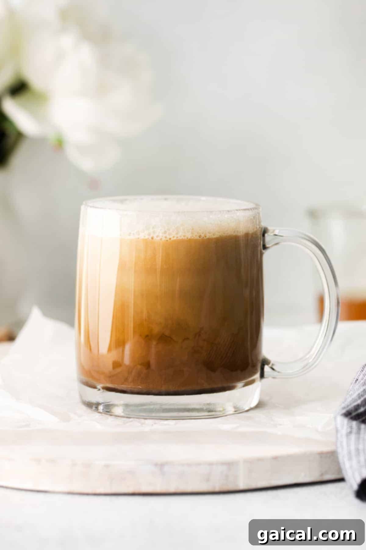 The perfect miel latte, ready to delight. A perfectly prepared miel latte in a clear glass coffee mug, ready to be enjoyed, showcasing its beautiful layers.